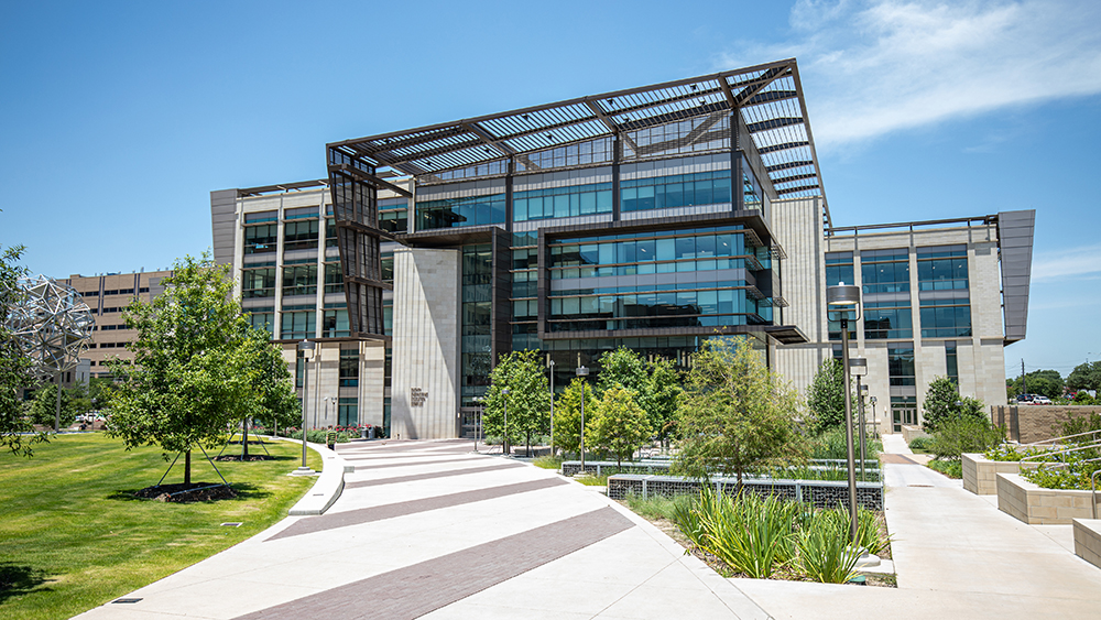 The front side of an angular large metal, stone and glass building. 