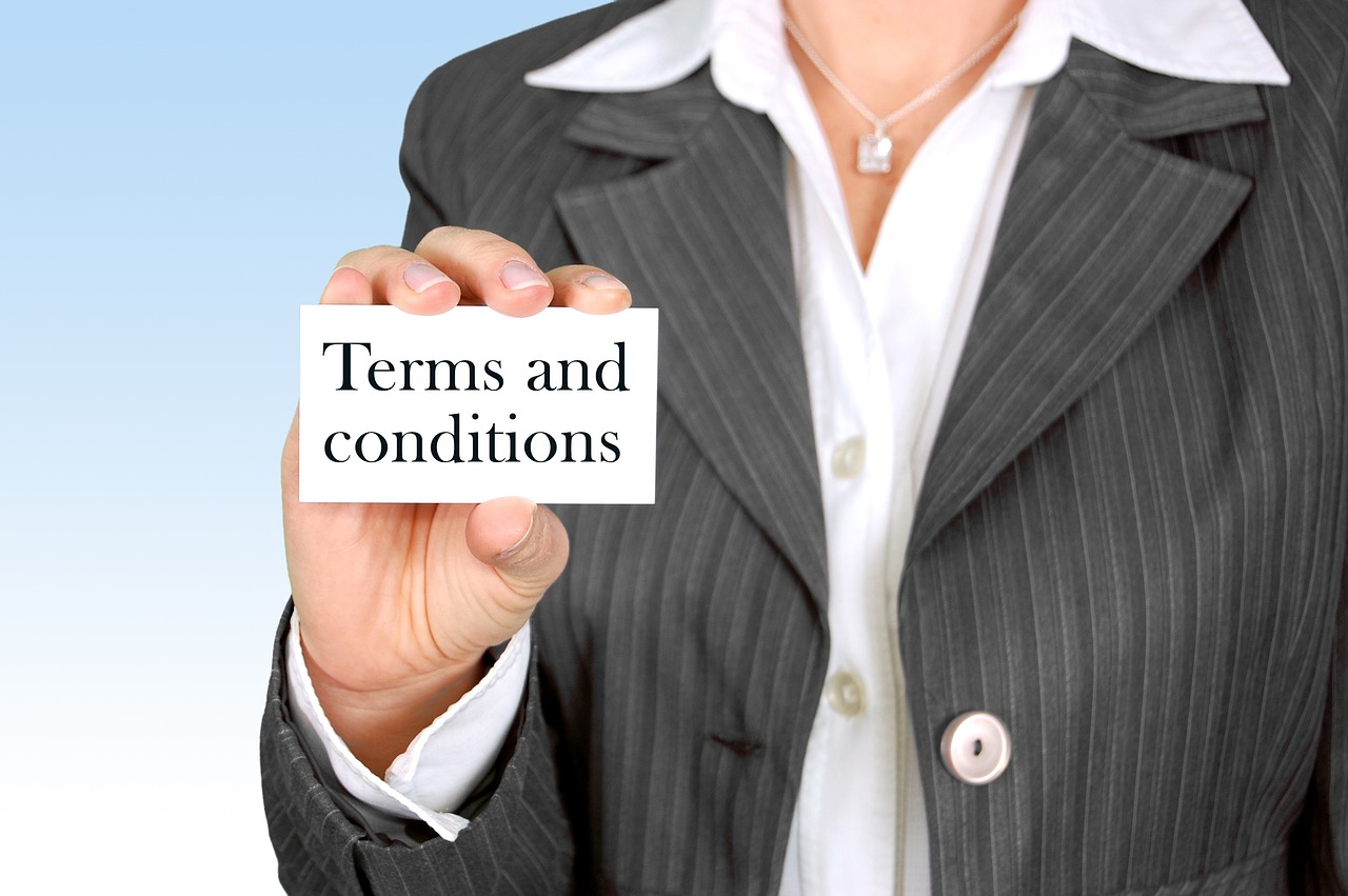 Closeup image of a hand holding a small white card that reads Terms and Conditions