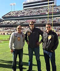 Photo of three individuals posing at Kyle Field