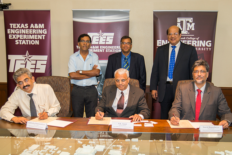 Three people at table signing document with three people behind them