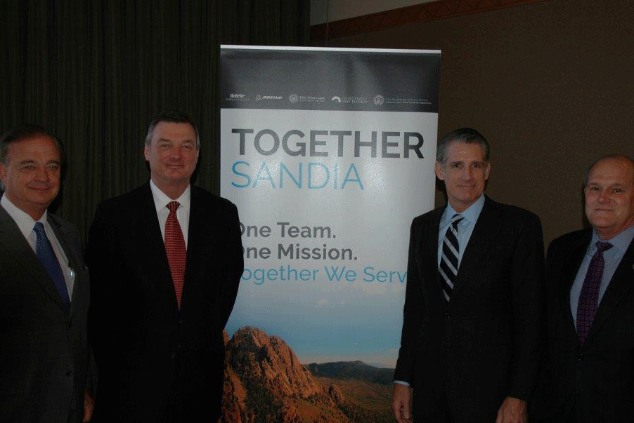 Representatives Taking A Picture In Front of Banner With Words Titled Together Sandia