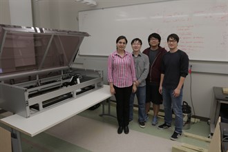 Photo of four individuals posing in front of a whiteboard 