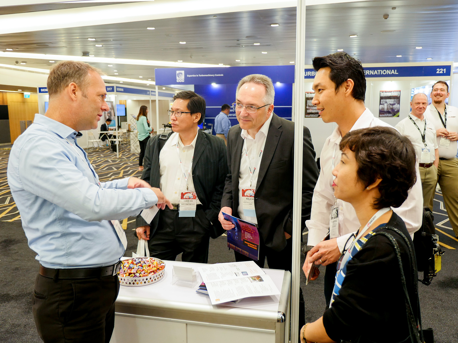 Booth host giving information to spectators at an exhibition