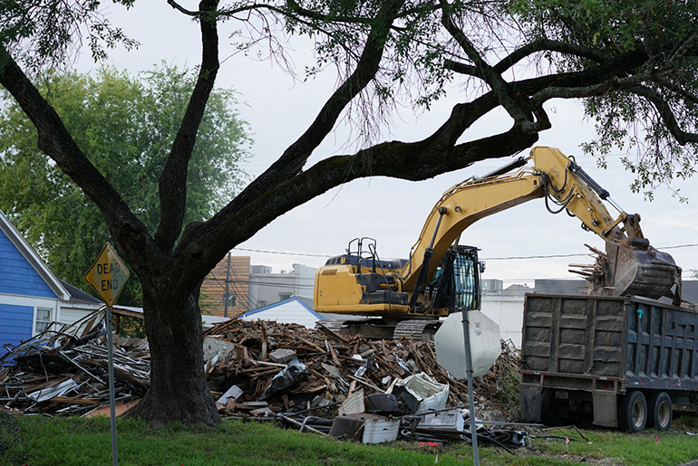 Back hoe cleaning up debris