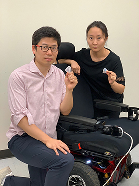 Two students crouched near a wheelchair