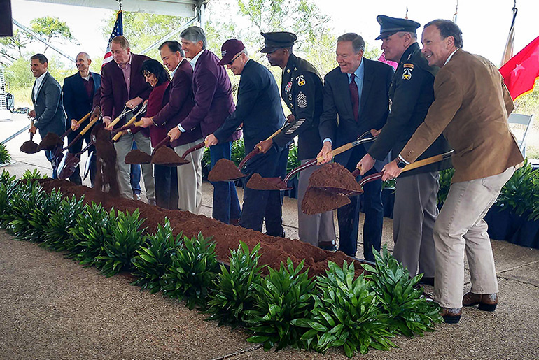 Officials with shovels digging