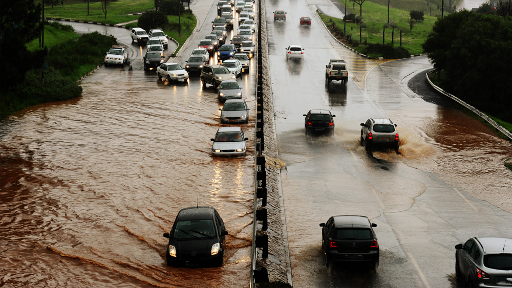 Cars drive through flooded streets.