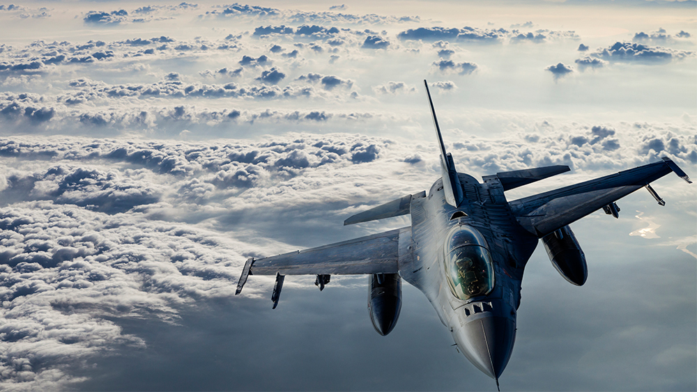 An F-16 plane flying above the clouds.