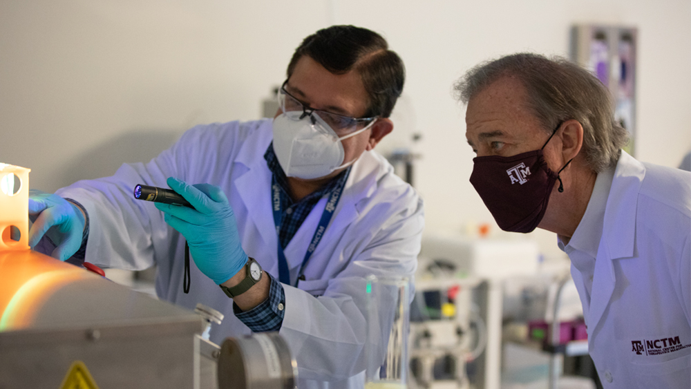 Research scientist Umesh Bageshwar shows Chancellor John Sharp how cells are broken apart during biomanufacturing.
