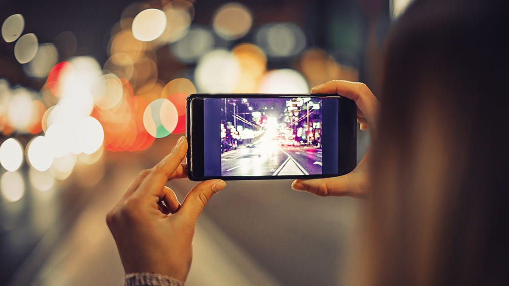 Girl taking a photo of a city with a smartphone