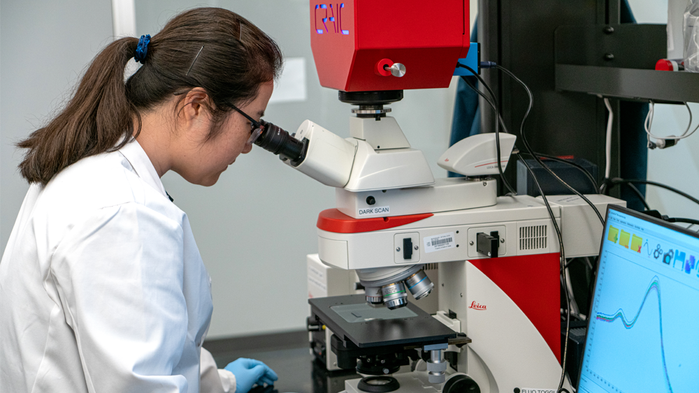 Professor looking at microscope in lab