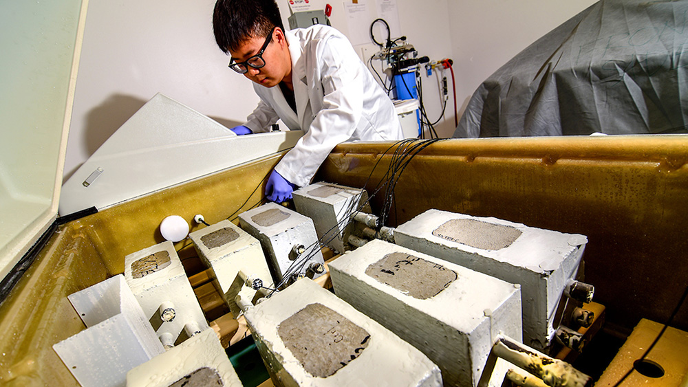 Researcher with concrete samples in a lab environment.
