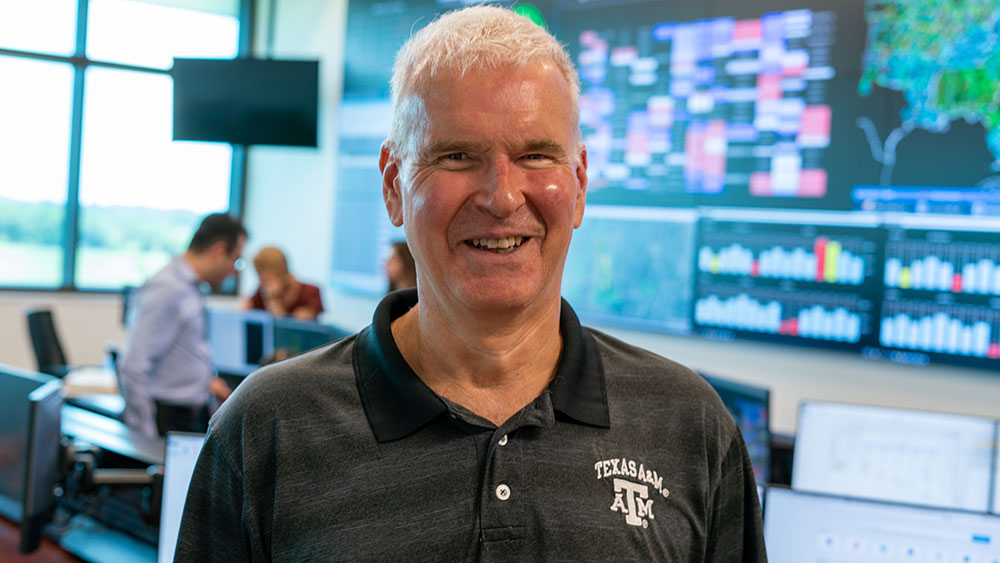 Thomas Overbye in front of computer screens in the Smart Grid Center.