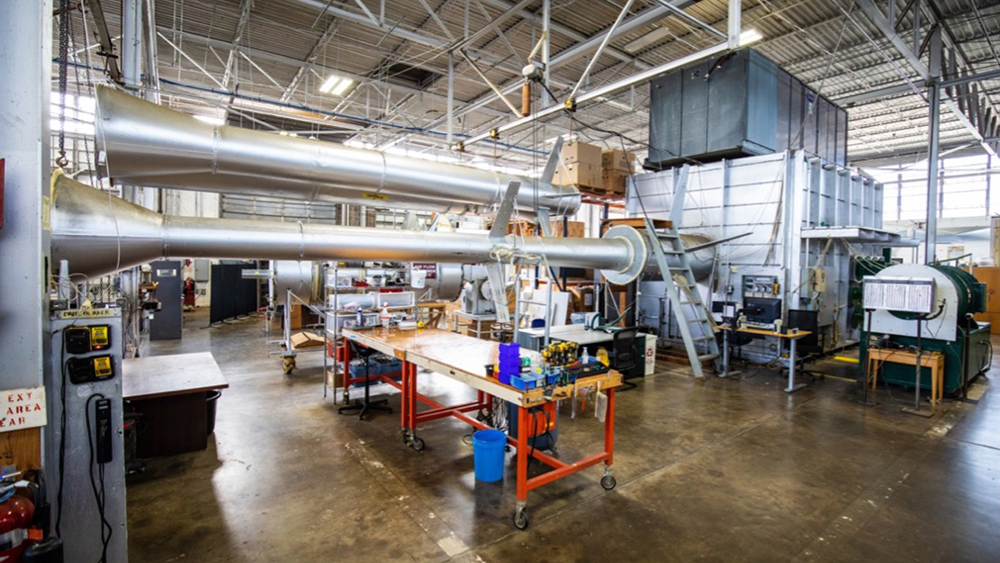 The inside of a large hangar with machines and tools for testing airflow systems.